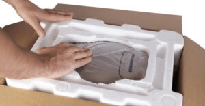 Manos empacando producto electrónico con protección de EPS en caja de cartón, mostrando embalaje seguro para eCommerce.
