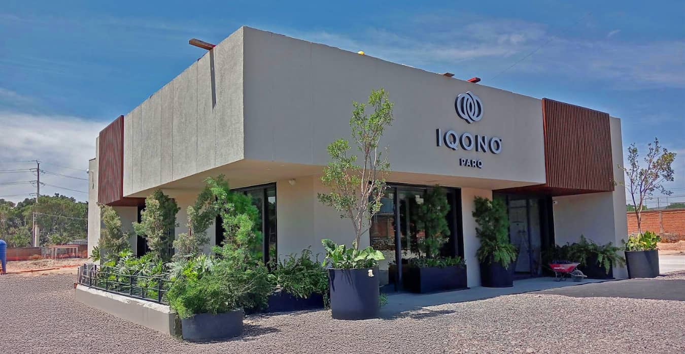 Fachada de edificio comercial moderno con diseño sustentable y vegetación integrada, correspondiente a IQONO Parq en desarrollo urbano.
