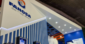 Stand de exhibición con el logotipo de FANOSA, mostrando un diseño moderno en colores blanco y azul, con iluminación LED y productos en exhibición en un ambiente de feria